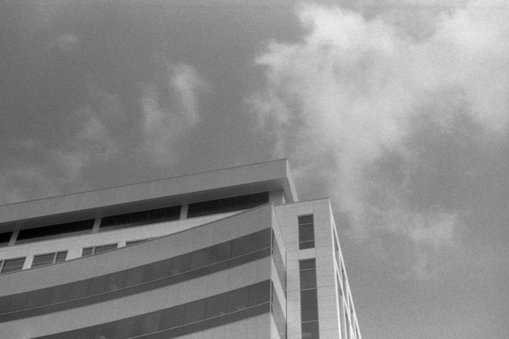 An austere white building looms into a gray sky.